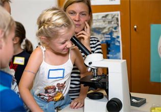 Kind schaut bei der KeKademy durch ein Mikroskop