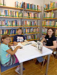 eine Gruppe von Kindern, die an einem Tisch in einer Bibliothek sitzen