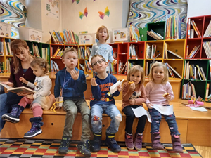 Eine Gruppe von Kindern sitzt auf einer Bank in einer Bibliothek